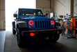 Three quarters view of a Jeep Wrangler with red LED headlight and fog light halos installed.