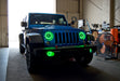 Three quarters view of a Jeep Wrangler JK with green LED headlight and fog light halo rings installed.