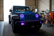 Three quarters view of a Jeep Wrangler with pink LED headlight and fog light halos installed.