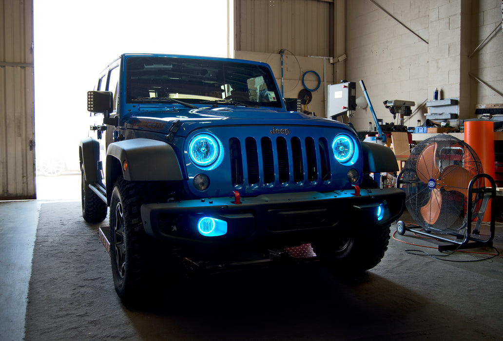 Three quarters view of a Jeep Wrangler with cyan LED headlight and fog light halos installed.