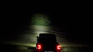 Rear view of a Jeep showing a beam of light coming from the 7" Multifunction LED Spotlights.