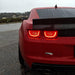 Rear view of a red Camaro in the rain. Close-up on tail lights with afterburner halos glowing
