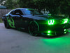 Three quarters view of a black Dodge Challenger with green LED headlight and fog light halo rings installed.