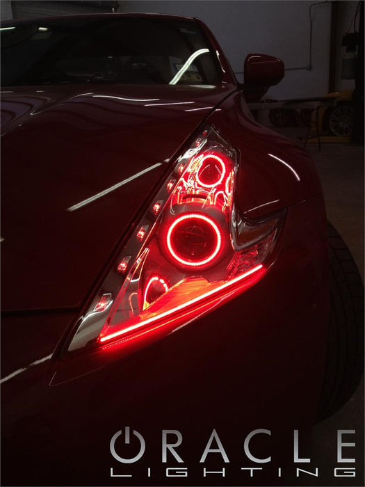 Close-up on a Nissan 370Z headlight with red LED halo rings installed.