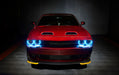 Front end of a red Dodge Challenger with cyan halo headlights.