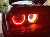 Front end of a black Dodge Challenger with red LED headlight halo rings installed.