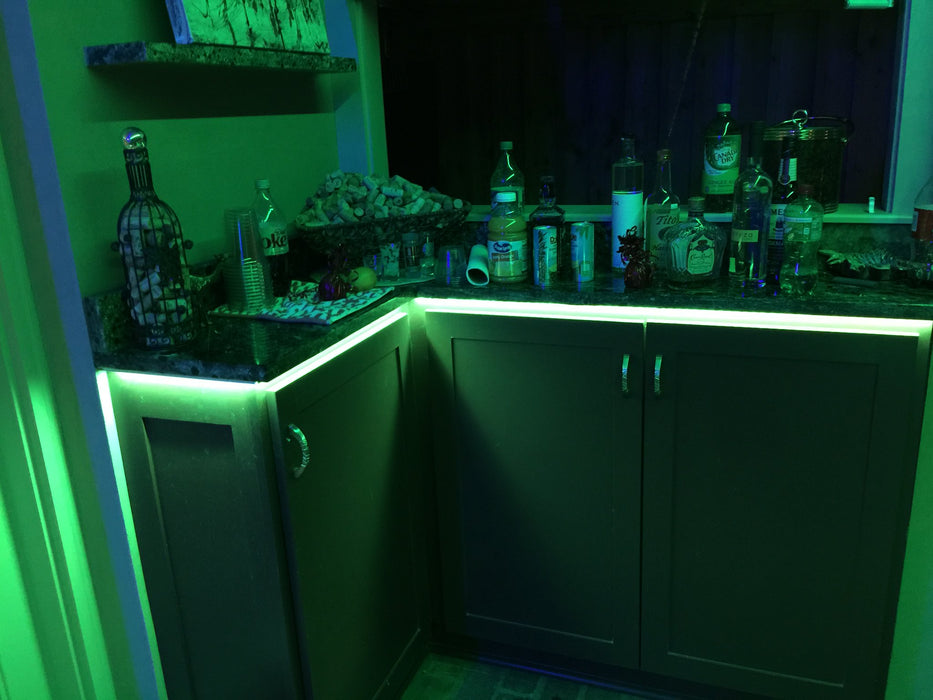 Home bar with green LED accent lighting underneath the counter