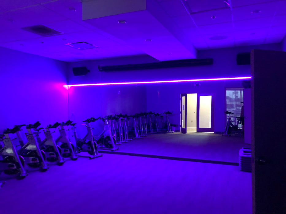 Workout room with purple LED lighting strips above the mirrors.