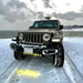 A Jeep parked in the snow, with LED Integrated Skid Plate installed and shining yellow light.