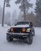 Jeep Wrangler in the snow with 7" High Powered LED Headlights installed, and amber halos on.