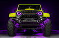 Front view of a yellow Jeep with 7" Oculus Headlights installed, set to purple LEDs.