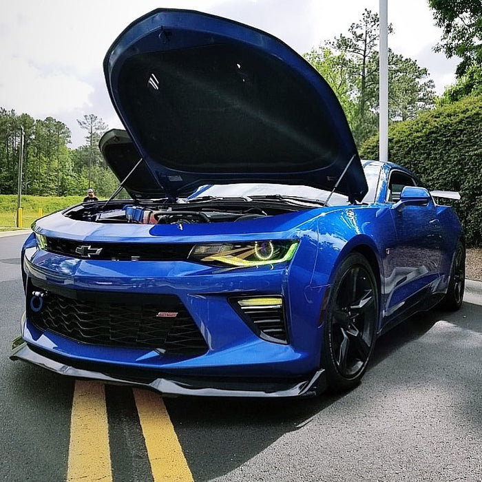 Blue camaro outdoors with yellow projector halos and DRL