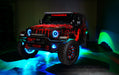 Three quarters view of a red Jeep Wrangler JL with High Performance 20W LED Fog Lights installed, and cyan halos on.