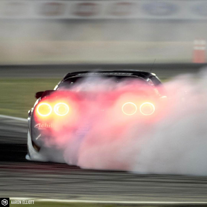Rear view of Corvette drifting on a racetrack, the afterburner tail light halo kit can be seen glowing through the smoke.