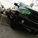 Front end of a black Dodge Ram with green LED headlight halo rings installed.