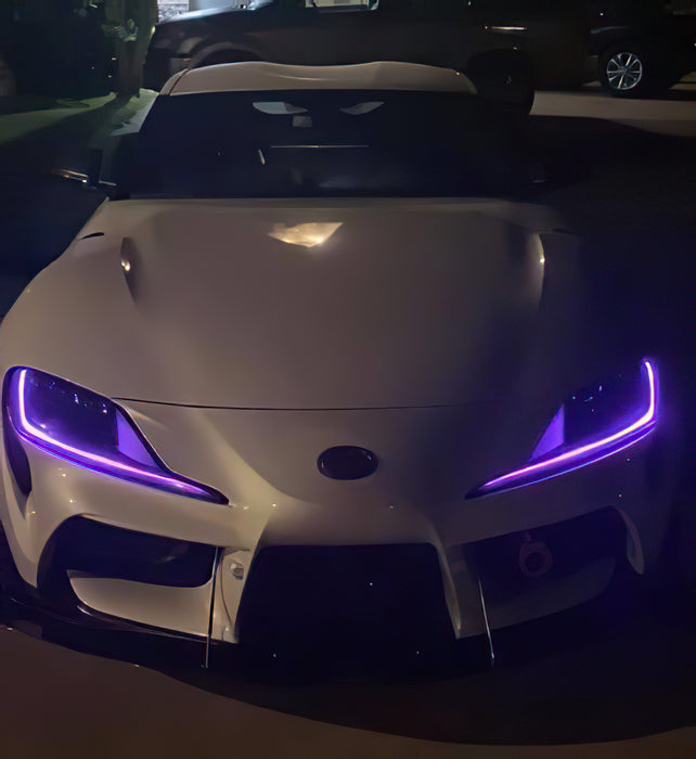 Front view of a white Toyota Supra with purple headlight DRLs.