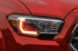 Close-up of a Toyota Tacoma headlight with amber DRLs.