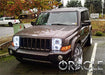 Three quarters view of a Jeep Commander with white LED headlight halo rings installed.