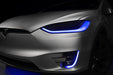 Close-up on the headlights and fog lights of a Tesla Model X with blue DRLs.