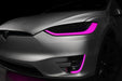 Close-up on the headlights and fog lights of a Tesla Model X with pink DRLs.