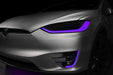 Close-up on the headlights and fog lights of a Tesla Model X with purple DRLs.