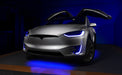 Silver Tesla Model X with blue headlight and fog light DRLs.