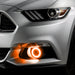 Close-up on the front bumper of a silver Ford Mustang equipped with amber fog light halos.