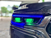 Extreme close-up of a Ram 1500 headlight with blue DRLs and green demon eye projectors.
