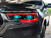 Extreme close-up of a Ram 1500 headlight with red DRLs and cyan demon eye projectors.