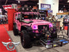 Pink Jeep in a showroom with pink LED headlight halo rings installed.