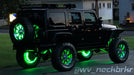 Rear three quarters view of a black Jeep with green LED Illuminated Spare Tire Wheel Ring Third Brake Light.